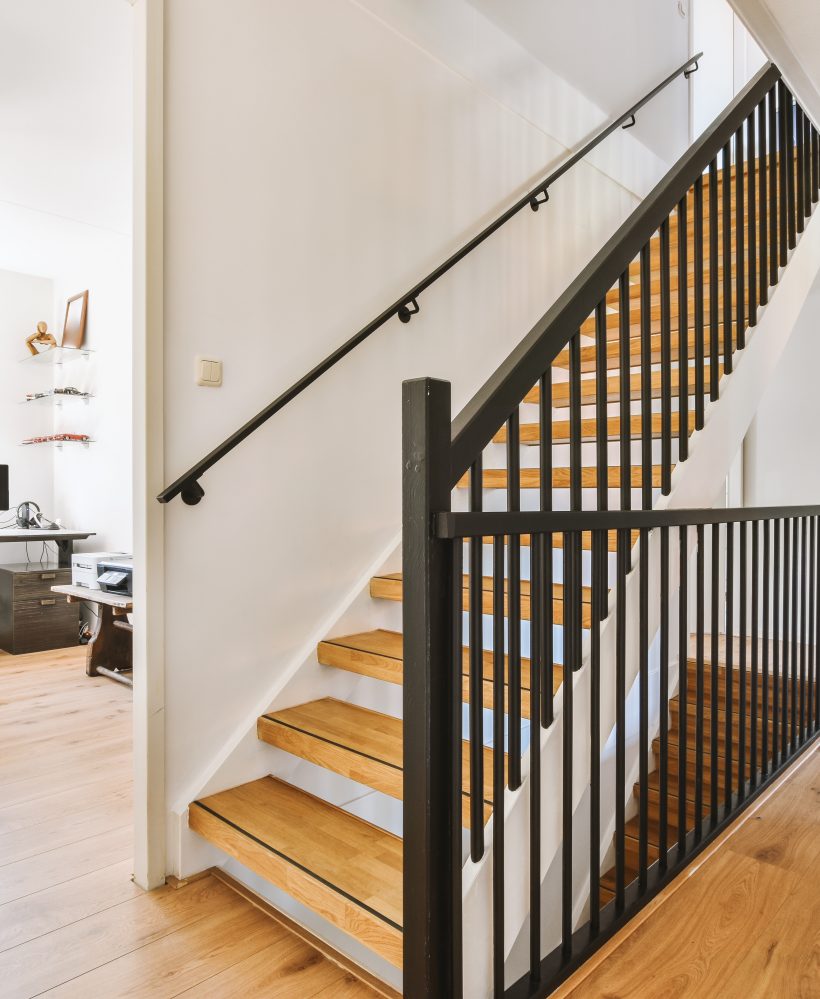 White hallway with wooden stairway leading to second floor of modern luxury apartment with minimalist interior design